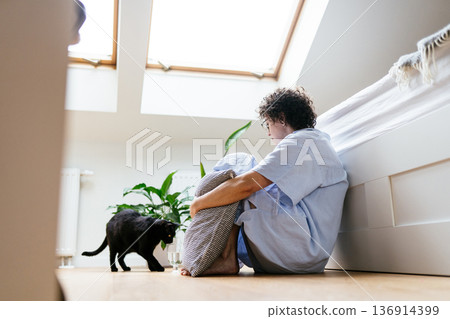 Middle aged woman sitting barefoot on bedroom floor, hugging pillow, black cat glass of water and antidepressants, seasonal depression episode, emotional isolation, mental health treatment at home Middle aged woman sitting barefoot on bedroom floor, hugging pillow, black cat glass of water and antidepressants, seasonal depression episode, emotional isolation, mental health treatment at home 136914399