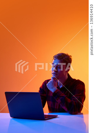 Young professional analyzing data on laptop against gradient background. Young professional analyzing data on laptop against gradient background. 136914410