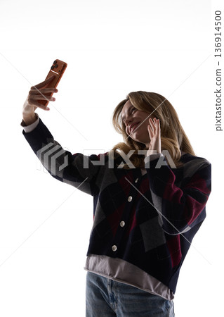 Young woman taking selfie with smartphone isolated on white background. 136914500