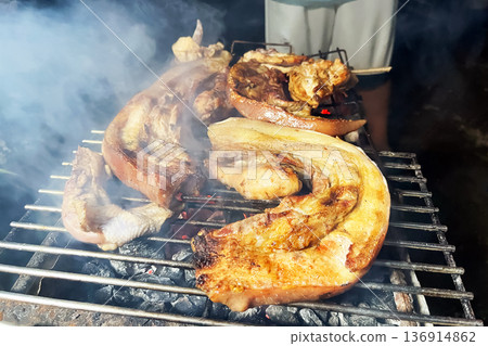 charcoal grilled pork belly strips and chops on a metal rack with smoke and hot burning coals charcoal grilled pork belly strips and chops on a metal rack with smoke and hot burning coals 136914862