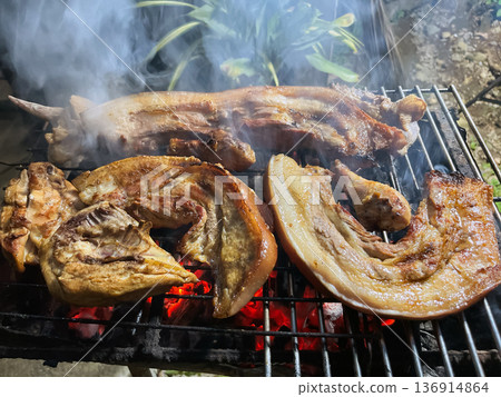 charcoal grilled pork belly strips, pork chops and chicken pieces on a metal rack with smoke and hot coals charcoal grilled pork belly strips, pork chops and chicken pieces on a metal rack with smoke and hot coals 136914864
