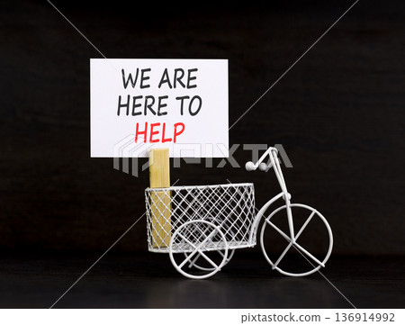 Support, help and we are here to help symbol. Concept words We are here to help on beautiful paper. Beautiful black background. Miniature bicycle. Business we are here to help concept. Copy space. 136914992