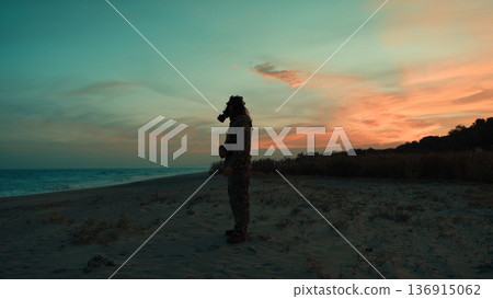 Soldier in silhouette at sunset on a beach contaminated by a nuclear attack 136915062