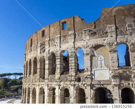Famous Coliseum in Rome. Colosseum, or Coliseum. Part of the wall of an antique stone structure with arches. Italy, Europe. Famous touristic place in the world, Europe. Beautiful blue sky background. Famous Coliseum in Rome. Colosseum, or Coliseum. Part of the wall of an antique stone structure with arches. Italy, Europe. Famous touristic place in the world, Europe. Beautiful blue sky background. 136915256