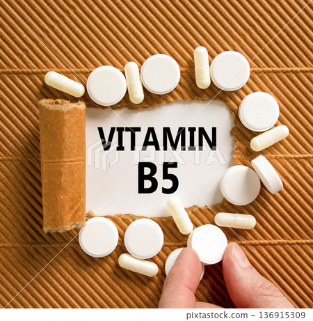 Vitamin B5 pantothenic acid symbol. Concept words Vitamin B5 on beautiful white paper. White pills tablets. Doctor's hand. Beautiful brown background. Medical healthy lifestyle Vitamin B5 concept. Vitamin B5 pantothenic acid symbol. Concept words Vitamin B5 on beautiful white paper. White pills tablets. Doctor's hand. Beautiful brown background. Medical healthy lifestyle Vitamin B5 concept. 136915309