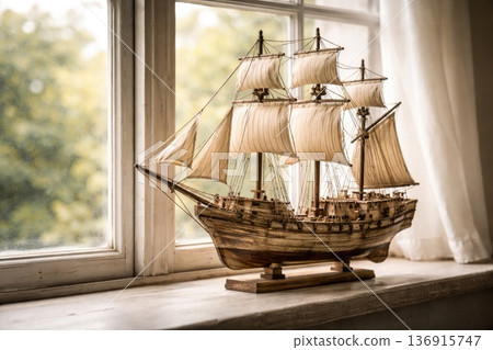 Vintage wooden sailing ship model displayed on windowsill with soft natural light 136915747