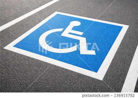 Blue disabled parking sign painted on asphalt with white wheelchair symbol Blue disabled parking sign painted on asphalt with white wheelchair symbol 136915782