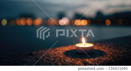 Single candle flame glowing at night with blurred city lights in background Single candle flame glowing at night with blurred city lights in background 136915895