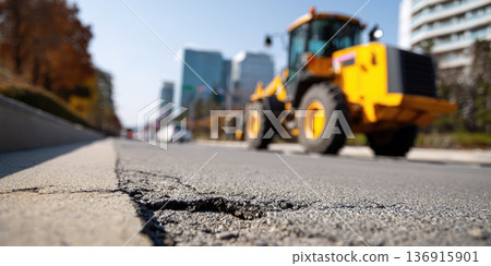 Large construction loader on city street with buildings in background 136915901