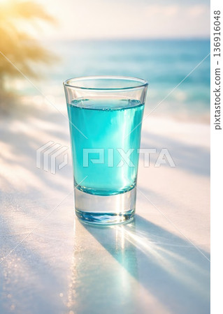 Blue tropical drink in glass on sunny beach with ocean background Blue tropical drink in glass on sunny beach with ocean background 136916048