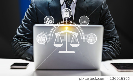 Businessman using a laptop with a glowing digital interface featuring scales of justice and corporate icons. Concept for law, compliance, ethics, and business security Businessman using a laptop with a glowing digital interface featuring scales of justice and corporate icons. Concept for law, compliance, ethics, and business security 136916565