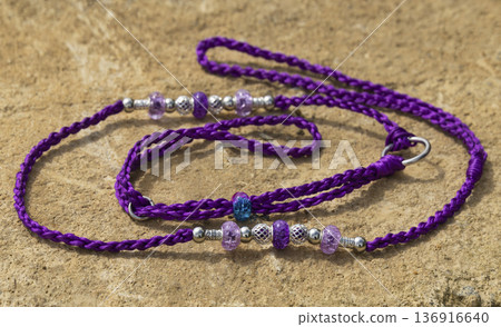 A vibrant purple handmade dog show lead displayed on a stone surface. The lead features intricate braiding and is adorned with purple, blue, and silver beads for professional exhibition use 136916640