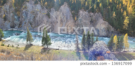 River flowing between steep rock and forested mountain. Nature landscape with wild blue water. Scenic view for travel destination. 136917099