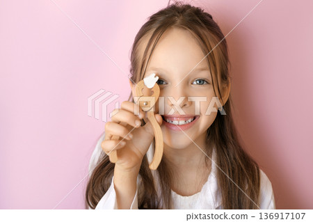 A cute funny girl holds dental forceps and a tooth. Wisdom tooth extraction. Loss of baby teeth. Dental implantation A cute funny girl holds dental forceps and a tooth. Wisdom tooth extraction. Loss of baby teeth. Dental implantation 136917107