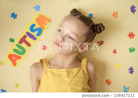 A thoughtful, sad, lonely girl looks towards the inscription with the word autism. World Autism Awareness Day. Difficulties of social communication A thoughtful, sad, lonely girl looks towards the inscription with the word autism. World Autism Awareness Day. Difficulties of social communication 136917111