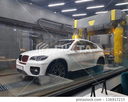 White car in an automatic car wash system. Modern vehicle cleaning service process for automobile maintenance. White car in an automatic car wash system. Modern vehicle cleaning service process for automobile maintenance. 136917215