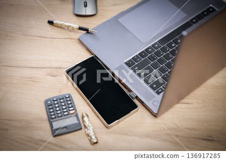 Laptop, phone and calculator on wooden desk for business work. Concept of modern workplace and digital technology for finance and accounting. 136917285