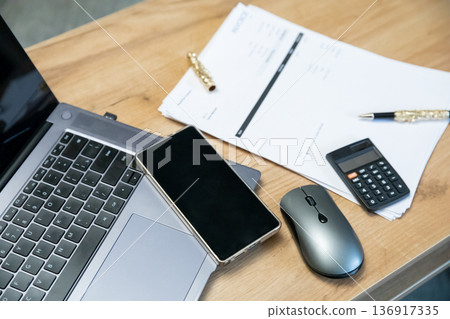 Office desk with laptop, smartphone, calculator, and papers. Business workspace concept for productivity and finance. Office desk with laptop, smartphone, calculator, and papers. Business workspace concept for productivity and finance. 136917335