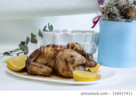 Whole roasted chicken with lemon wedges on a white plate. Food photography for recipe book, restaurant menu or cooking blog. Whole roasted chicken with lemon wedges on a white plate. Food photography for recipe book, restaurant menu or cooking blog. 136917411