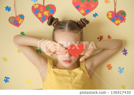 Portrait of girl covering eyes with heart on background decorated with puzzle pieces. Concept of autism, emotional sensitivity, neurodiversity acceptance, love and support for kids with autism Portrait of girl covering eyes with heart on background decorated with puzzle pieces. Concept of autism, emotional sensitivity, neurodiversity acceptance, love and support for kids with autism 136917430