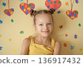Portrait of smiling girl with colorful puzzle glasses on yellow background. Concept of autism awareness, neurodiversity, inclusion, sensory perception and support for children with autism disorder. 136917432
