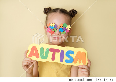 Child with Autism lettering against puzzle symbol background. Clinical context of autism spectrum disorder, neurodevelopmental condition, behavioral evaluation, sensory processing differences Child with Autism lettering against puzzle symbol background. Clinical context of autism spectrum disorder, neurodevelopmental condition, behavioral evaluation, sensory processing differences 136917434