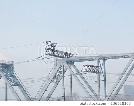 Large metal bridge structure with power lines against a clear sky for industrial engineering or urban infrastructure design. Large metal bridge structure with power lines against a clear sky for industrial engineering or urban infrastructure design. 136918303