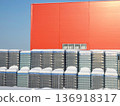 Red industrial building exterior and stacks of empty glass bottle crates covered with snow. Manufacturing, winter, and storage conditions. 136918317