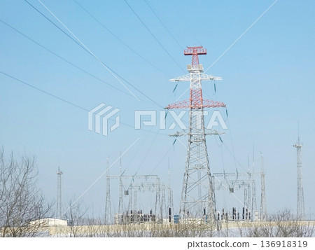 High voltage electrical power line tower and substation against a clear sky. Energy transmission infrastructure for electricity supply. 136918319