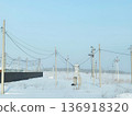 Electric power utility poles and cables in a snowy field. Power lines supplying electricity to rural areas. Energy infrastructure. 136918320