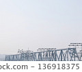 Metal railroad bridge structure extending across the frame with an empty, overcast sky above and power lines, engineering concept. 136918375