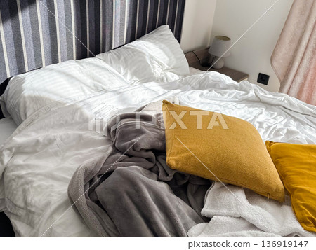 Unmade bed with pillows and blanket in modern bedroom interior. Morning routine, rest recovery, home comfort, everyday lifestyle concept 136919147