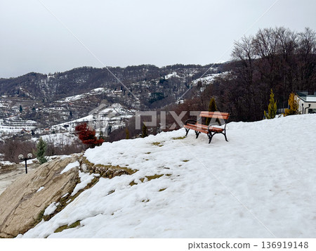Wooden bench overlooking snowy valley and mountain landscape. Winter solitude, travel destination, peaceful contemplation, nature retreat concept Wooden bench overlooking snowy valley and mountain landscape. Winter solitude, travel destination, peaceful contemplation, nature retreat concept 136919148