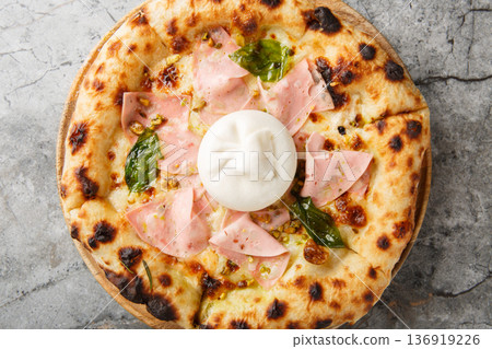 Charred crispy mortadella and burrata pizza with basil and pistachios close-up on a wooden board. Horizontal top view 136919226