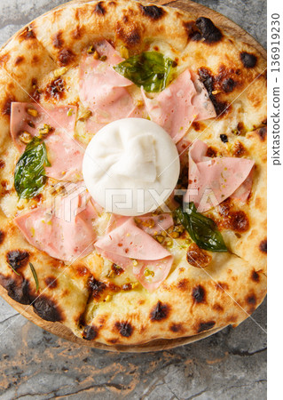 Close-up of neapolitan pizza with whole burrata cheese, mortadella and crushed pistachios. Vertical top view Close-up of neapolitan pizza with whole burrata cheese, mortadella and crushed pistachios. Vertical top view 136919230