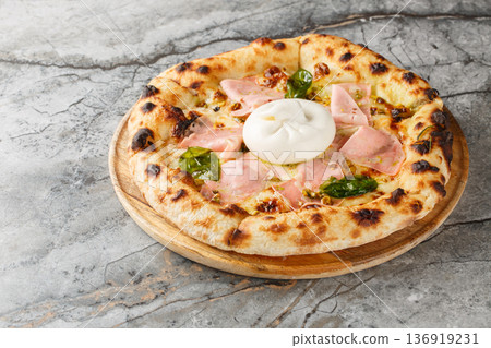 Charred crispy mortadella and burrata pizza with basil and pistachios close-up on a wooden board. Horizontal 136919231