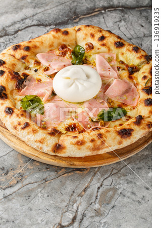 Close-up of neapolitan pizza with whole burrata cheese, mortadella and crushed pistachios. Vertical Close-up of neapolitan pizza with whole burrata cheese, mortadella and crushed pistachios. Vertical 136919235