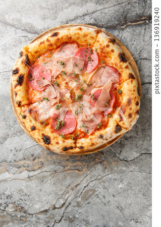 Close-up of neapolitan pizza with prosciutto, salami, tomato sauce and mozzarella on wooden board. Garnished with fresh thyme. Marble background top view Close-up of neapolitan pizza with prosciutto, salami, tomato sauce and mozzarella on wooden board. Garnished with fresh thyme. Marble background top view 136919240