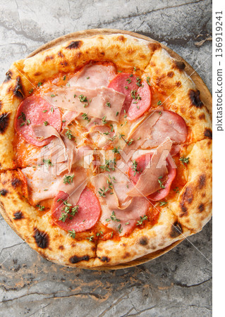 neapolitan meat pizza with prosciutto salami herbs close-up on a wooden board. Vertical top view neapolitan meat pizza with prosciutto salami herbs close-up on a wooden board. Vertical top view 136919241