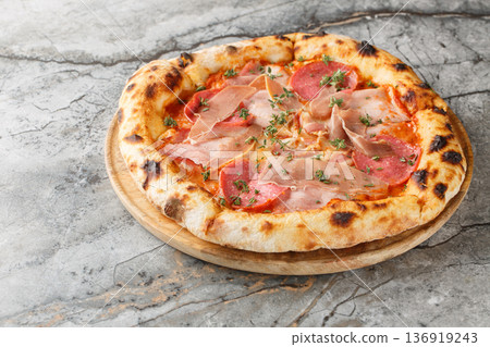 Charred meat pizza with prosciutto, salami, bacon and ham close-up on a wooden board. Horizontal 136919243