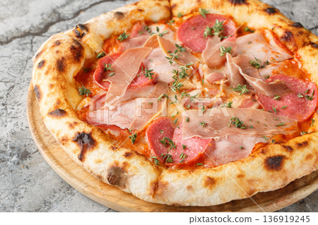 Crispy charred meat pizza with prosciutto, salami, bacon and ham close-up on a wooden board. Horizontal Crispy charred meat pizza with prosciutto, salami, bacon and ham close-up on a wooden board. Horizontal 136919245