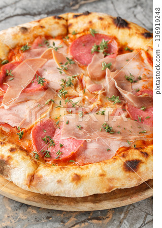 neapolitan meat pizza with prosciutto salami herbs close-up on a wooden board. Vertical neapolitan meat pizza with prosciutto salami herbs close-up on a wooden board. Vertical 136919248