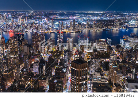Aerial night panorama of Manhattan skyline with illuminated buildings and East River waterfront in New York City USA 136919452