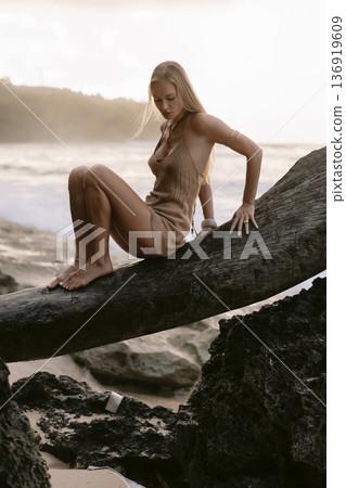 Pretty blonde woman posing between rocks on beach 136919609