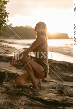 Beautiful young woman posing on rocky beach at sunset, sunshine portrait Beautiful young woman posing on rocky beach at sunset, sunshine portrait 136919614