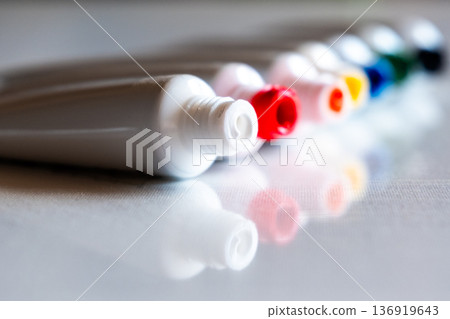 A row of paint tubes in various colors including red, yellow, green, and blue. The tubes are arranged neatly on a white surface, showcasing their vibrant caps. A row of paint tubes in various colors including red, yellow, green, and blue. The tubes are arranged neatly on a white surface, showcasing their vibrant caps. 136919643