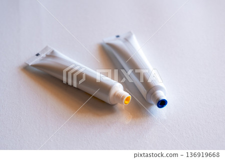 Blue and yellow tubes of paint on a white surface. The colors represent the Ukrainian flag. The tubes are closed with colored caps. 136919668