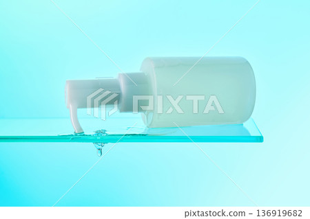 Skincare pump bottle dropping water on glass shelf 136919682