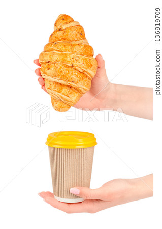 Female hands holding croissant and takeaway coffee cup 136919709