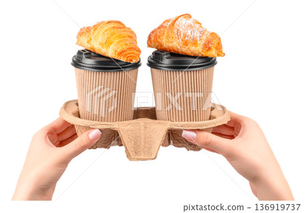 Two takeaway coffee cups with croissants in hands isolated on white background Two takeaway coffee cups with croissants in hands isolated on white background 136919737